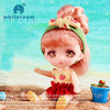 A small, pink-haired doll with a green headband and red dress stands against a bright blue background.