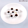A white plate holds six mini resin coffee cups filled with dark liquid for dollhouse kitchens