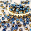 A pile of vibrant round blue and gold beads for jewelry making displayed on a white surface.