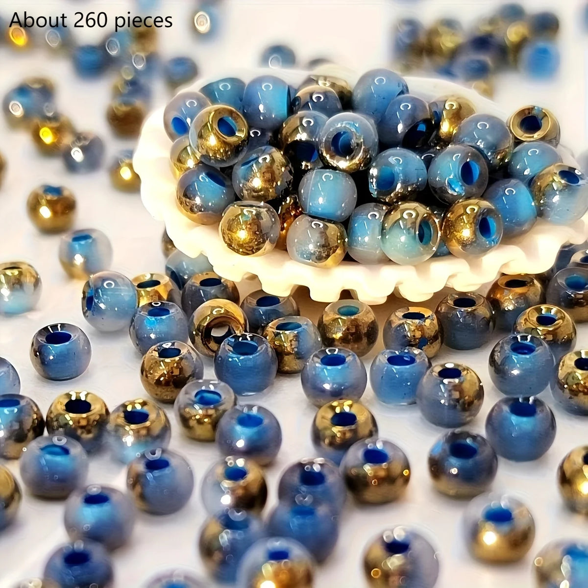 A pile of vibrant round blue and gold beads for jewelry making displayed on a white surface.