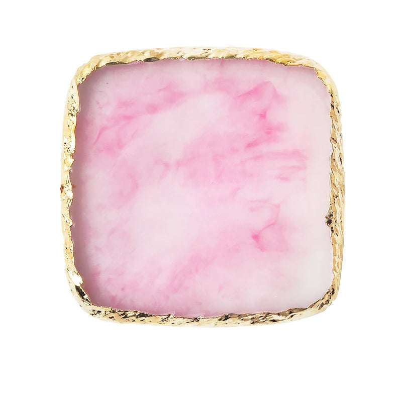 A square resin palette with pink marbled resin and a gold trim.