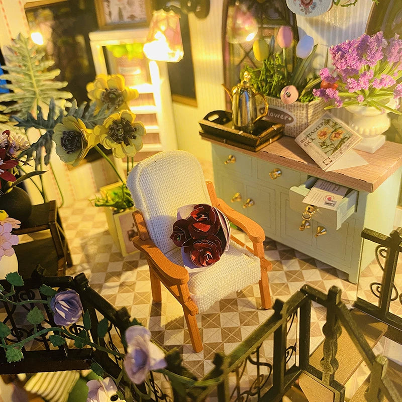 A detailed miniature dollhouse kit featuring furniture and warm lighting displayed in a cozy interior setting.