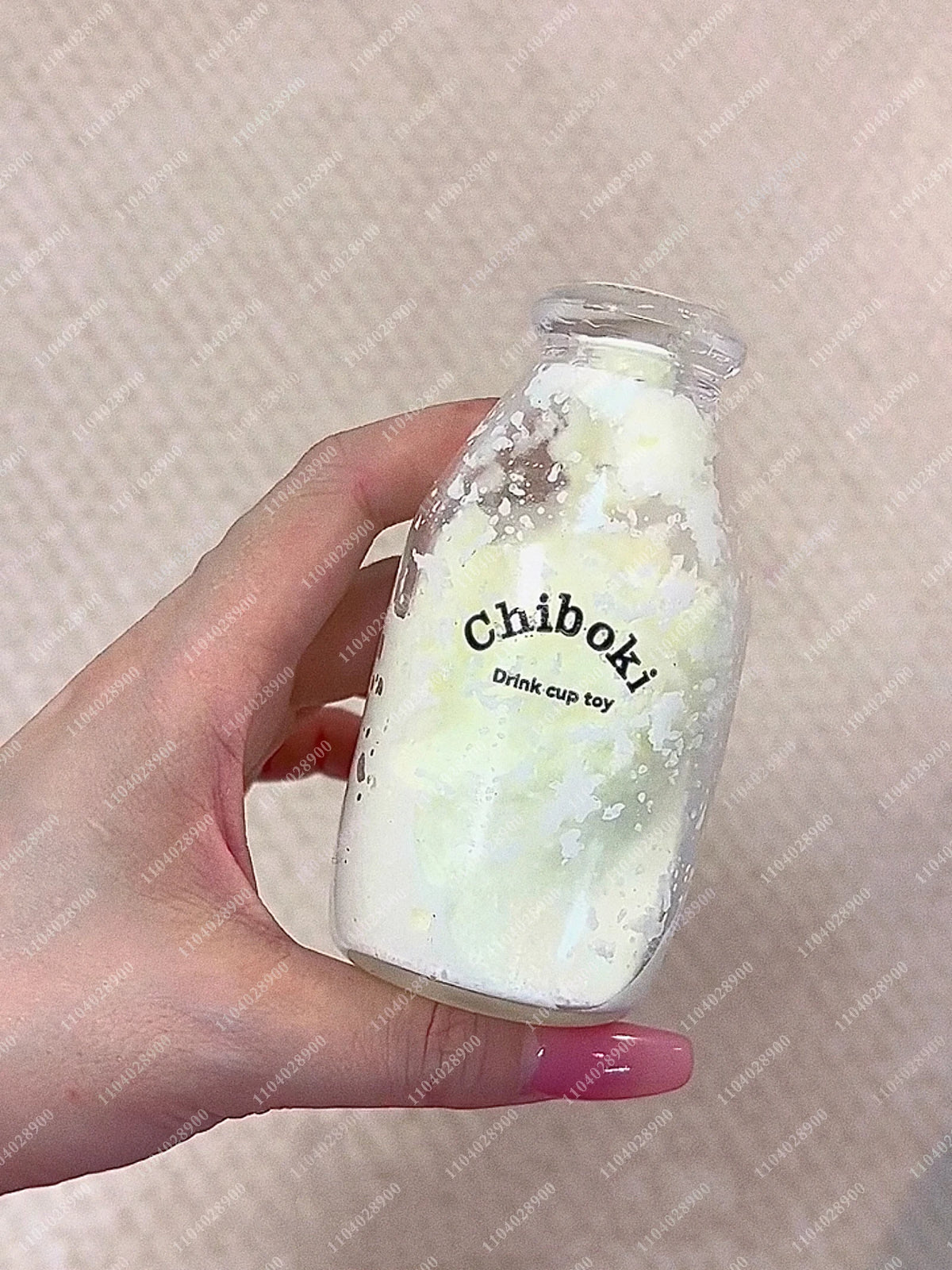 A hand holds a clear glass bottle filled with white, milky substance labeled Chiboki drink cup toy.