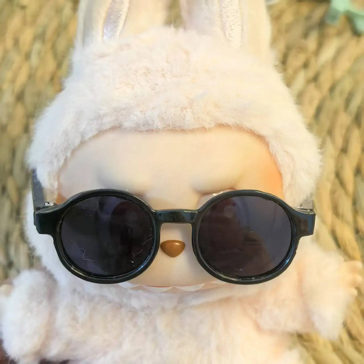 A Labubu doll wearing a white fluffy hoodie and black sunglasses.
