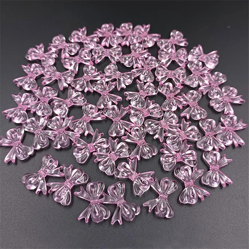 A pile of 20 clear pink acrylic bow beads for jewelry making.