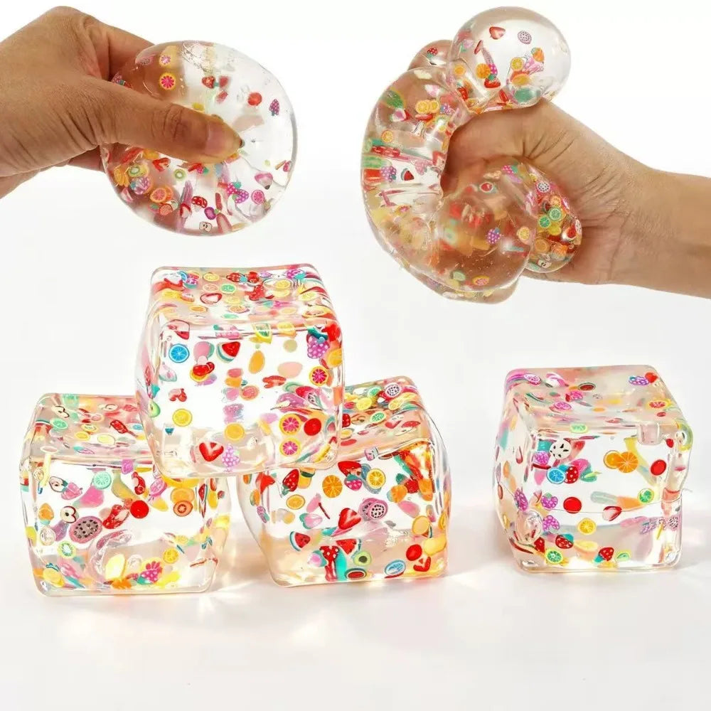 Hand squeezing a translucent, colorful fruit ice cube stress ball and several finished cubes.