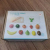 A box containing a magnetic fruit cutting play set with various wooden fruits and a knife.