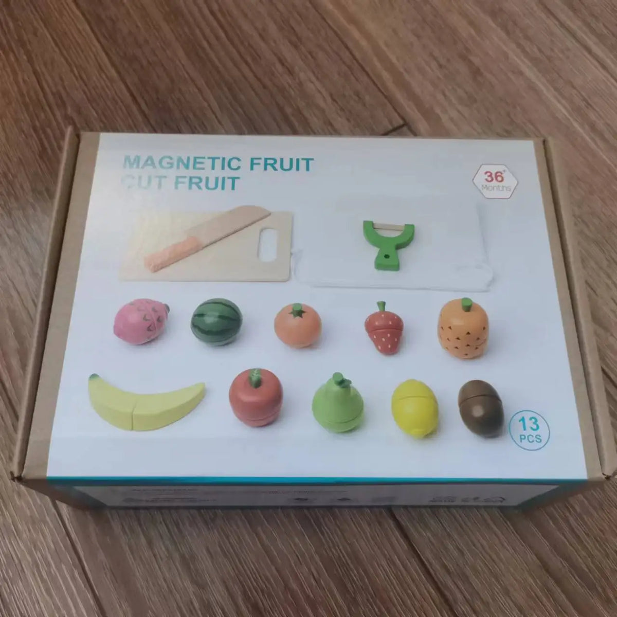 A box containing a magnetic fruit cutting play set with various wooden fruits and a knife.