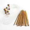 A set of flexible bamboo Tunisian crochet hooks and a long length of clear fishing line are displayed on a white background.