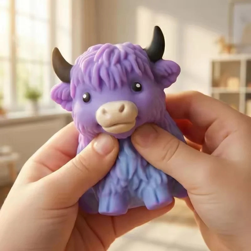A hand holds a purple glitter highland cow squishy stress relief toy with black horns.