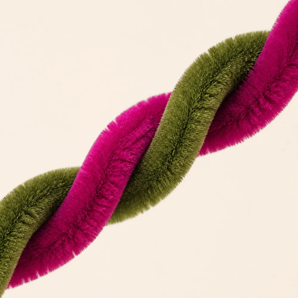 A close-up of a twisted craft set featuring vibrant magenta and olive green chenille stems.