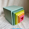 A set of pastel wooden stacking blocks in various shades of mint green, yellow, and pink stacked together.