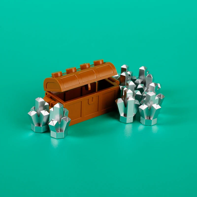 An open wooden treasure chest filled with silver coins and surrounded by various silver building block coins on a teal backgr