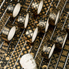 A collection of black and gold foil washi tape rolls scattered on a patterned surface next to a white bust.