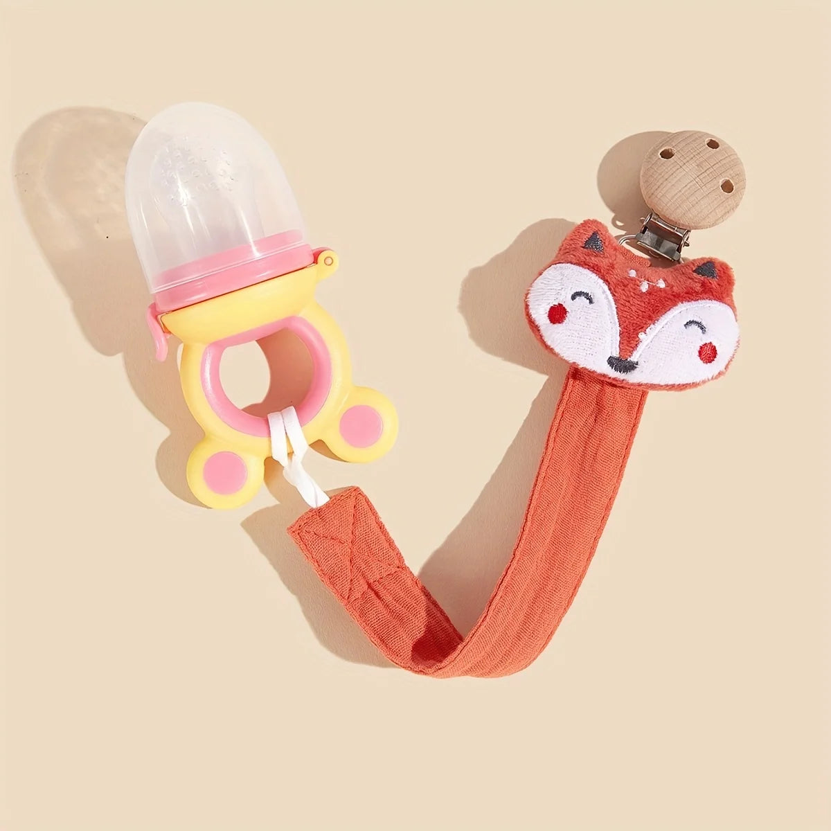 An orange elephant pacifier holder with a clear dome and wooden clip is shown against a light background.