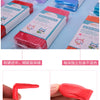 A close-up view of bright red polymer clay modeling clay in various packaging and a hand holding a piece of the clay.