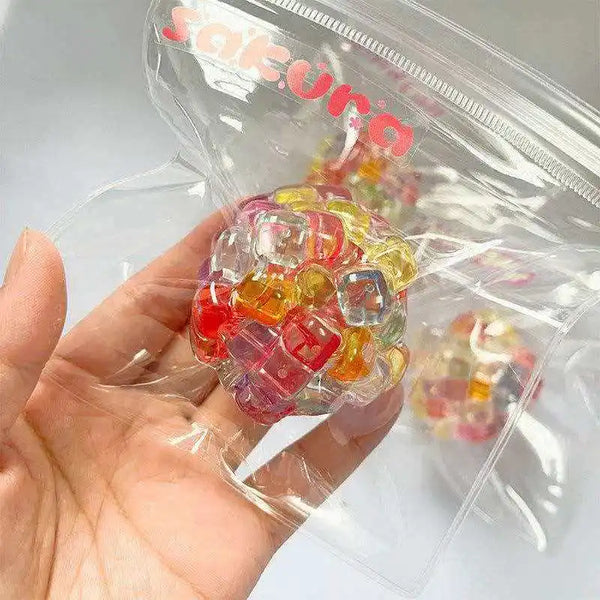 A hand holds a clear plastic bag filled with colorful, translucent ice cube fidget toys.