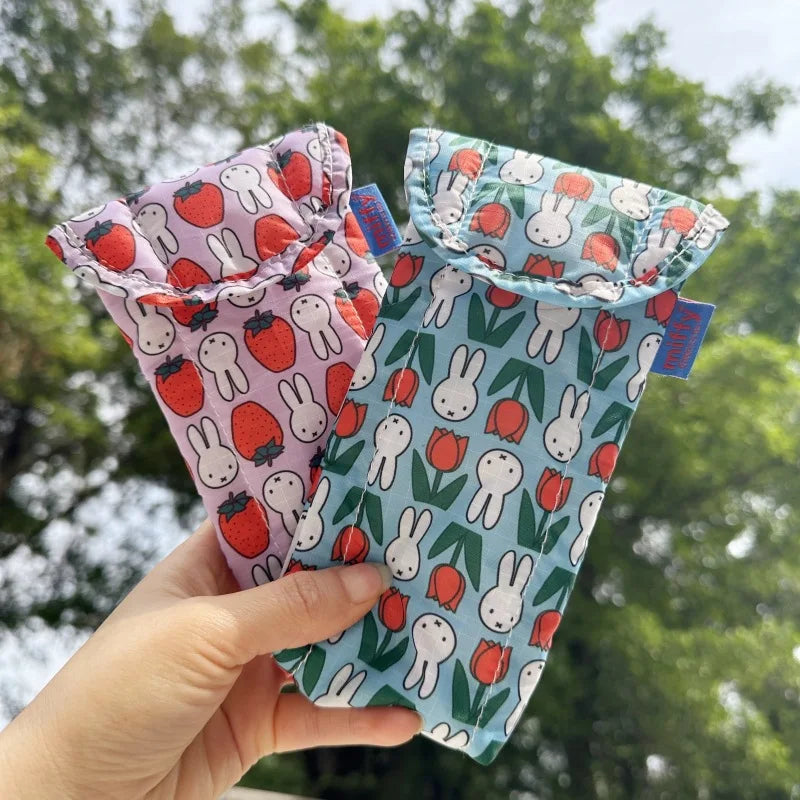 A hand holds a fabric storage bag featuring Miffy rabbits and strawberries, designed for magnetic storage.