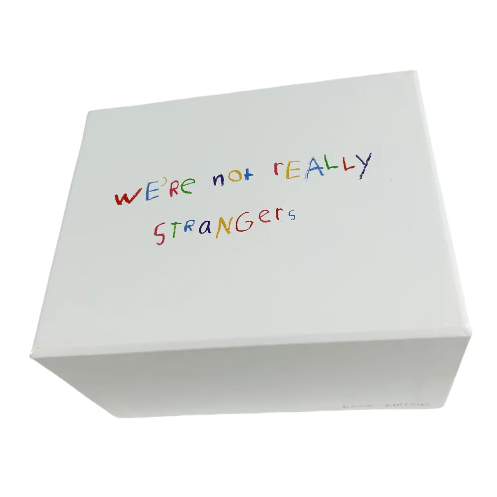 Weiße Box mit handschriftlichem Text auf dem Deckel: Wir sind nicht wirklich Fremde.
