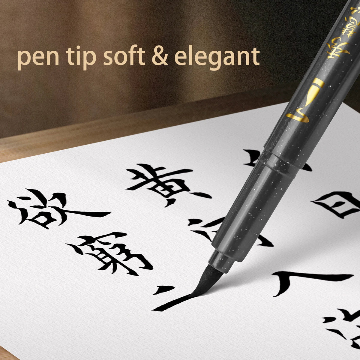 A close-up of a black pen with a soft tip writing Japanese calligraphy characters on white paper.