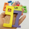 A hand holds two wooden number building blocks, 9 and 7, in yellow and purple colors.