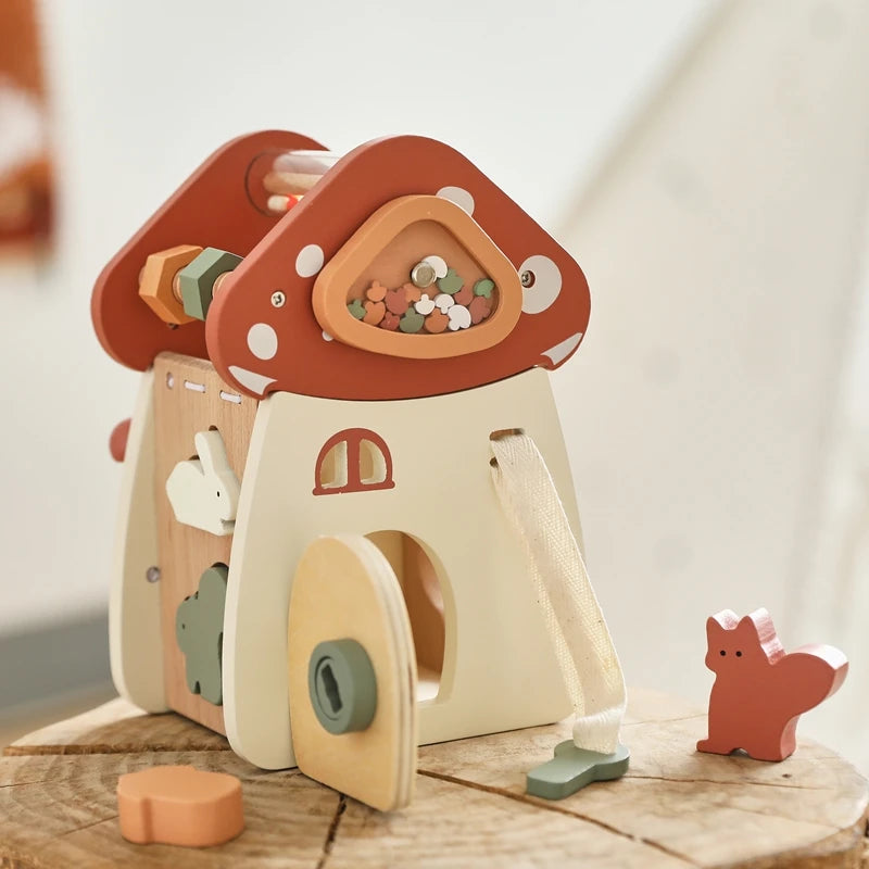 A wooden mushroom castle stacking toy puzzle with various pieces and a small animal figure on a wooden surface.