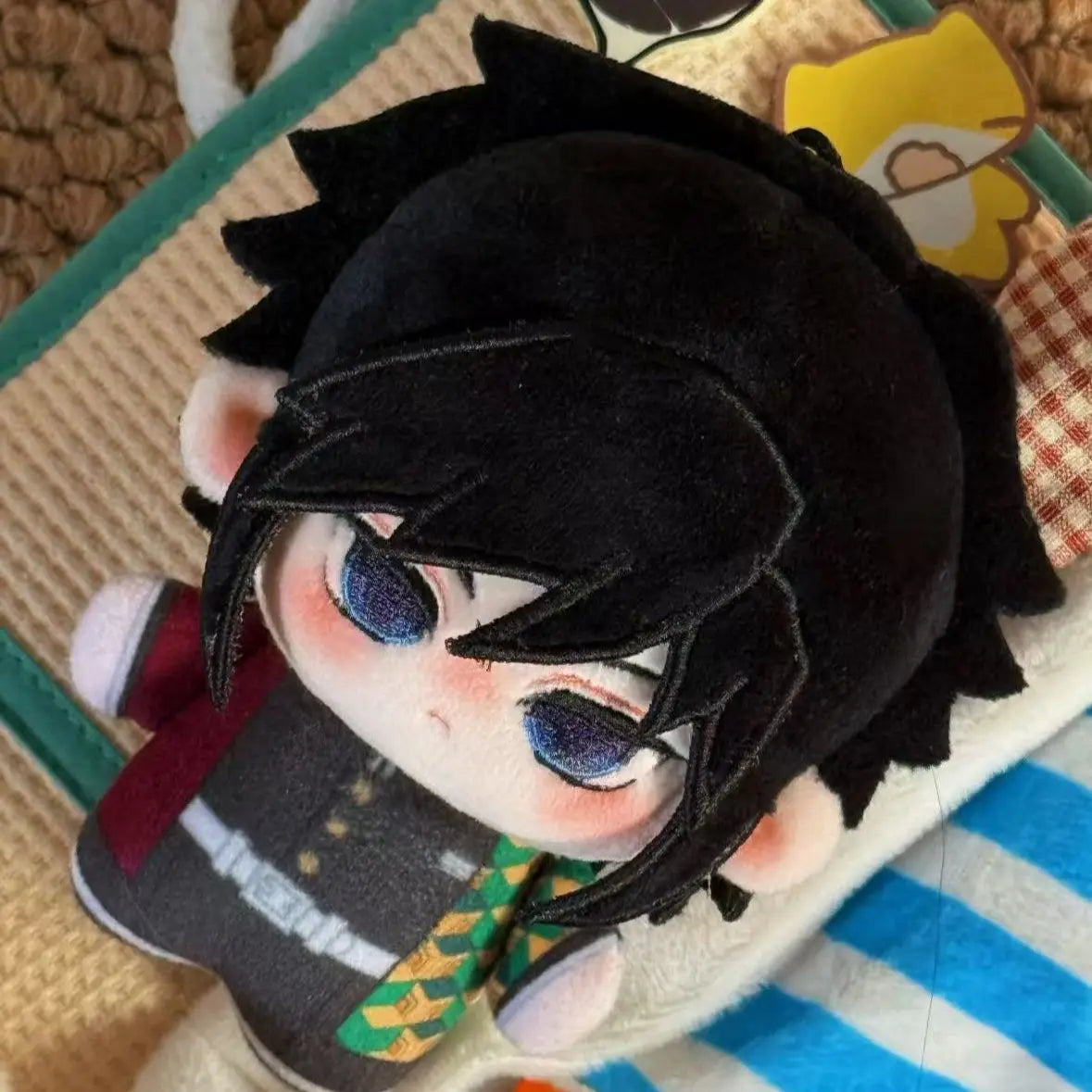 A cute anime plush doll of a character with black hair and blue eyes wearing a dark outfit.