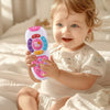 A smiling baby is holding a pink electronic remote control toy with lights and music.