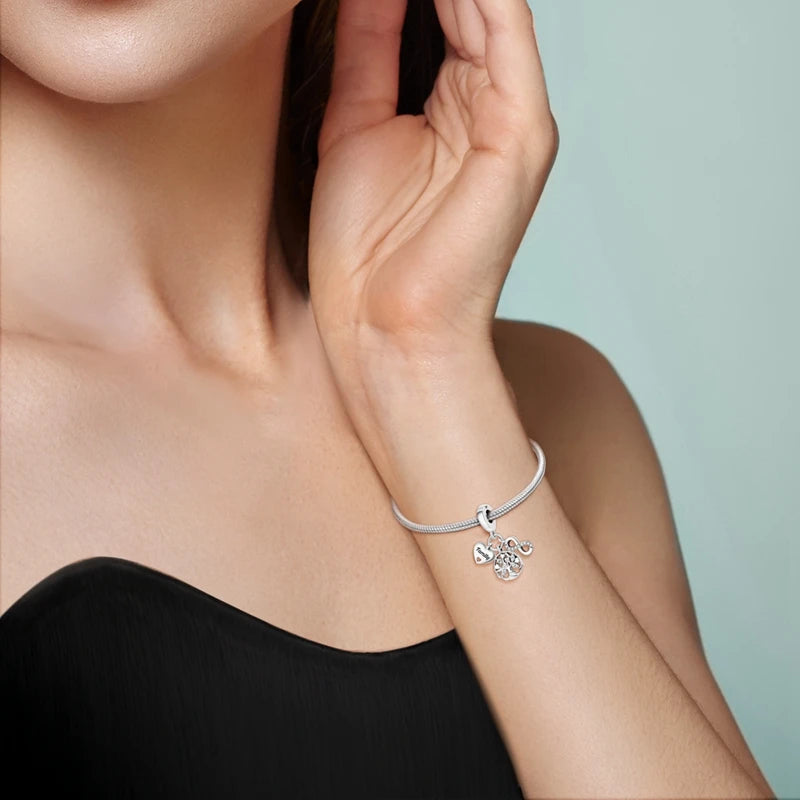 A close-up of a woman's wrist showing a silver heart charm bracelet.
