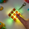 A finger is pressing a square LED mechanical keycap fidget keychain, illuminating the surrounding area with soft light.