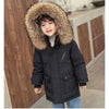 A child wearing a black hooded winter jacket with a large brown faux fur collar and blue jeans.