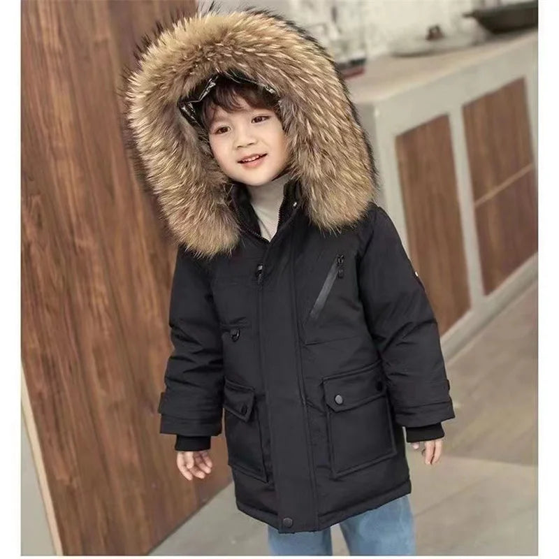 A child wearing a black hooded winter jacket with a large brown faux fur collar and blue jeans.