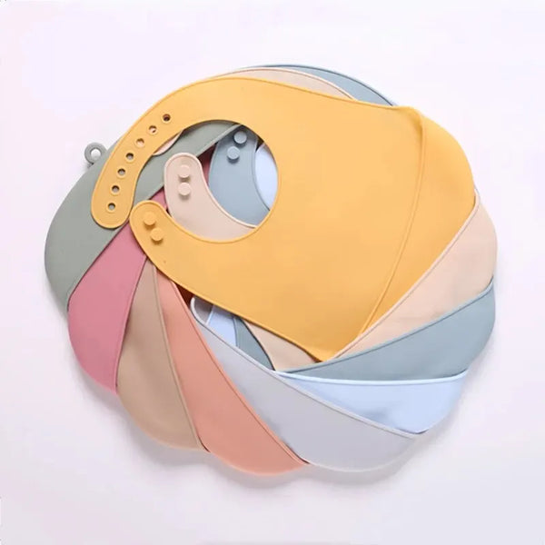 Stapel pastellfarbener Silikon-Lätzchen für Babys in Gelb, Pink und Blau mit Auffangtaschen