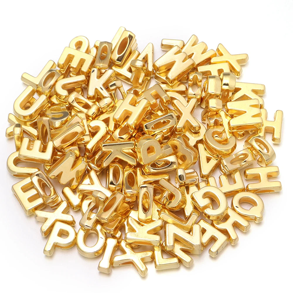 A pile of mixed gold acrylic letter beads for DIY crafts.