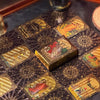 A close-up of a mini gold foil tarot card deck laid out on a dark surface with several cards visible.