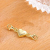 A gold-colored magnetic heart jewelry clasp necklace resting on a wooden surface.