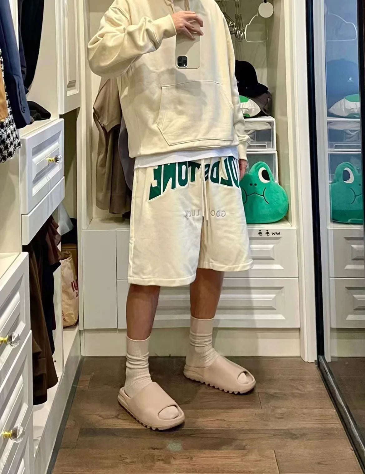A person wearing a cream hoodie and white shorts with green trim stands in a store display featuring comfortable EVA platform