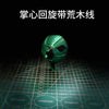 A green steel ball fidget toy with a black design resting on a grid surface.