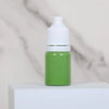 A small green bottle with a white cap sits on a white surface.