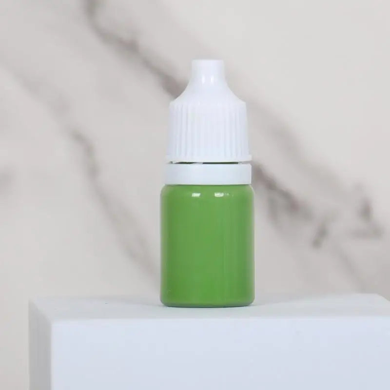 A small green bottle with a white cap sits on a white surface.