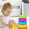 A toddler is playing with a colorful rainbow revolving music stacking toy made of plastic rings.