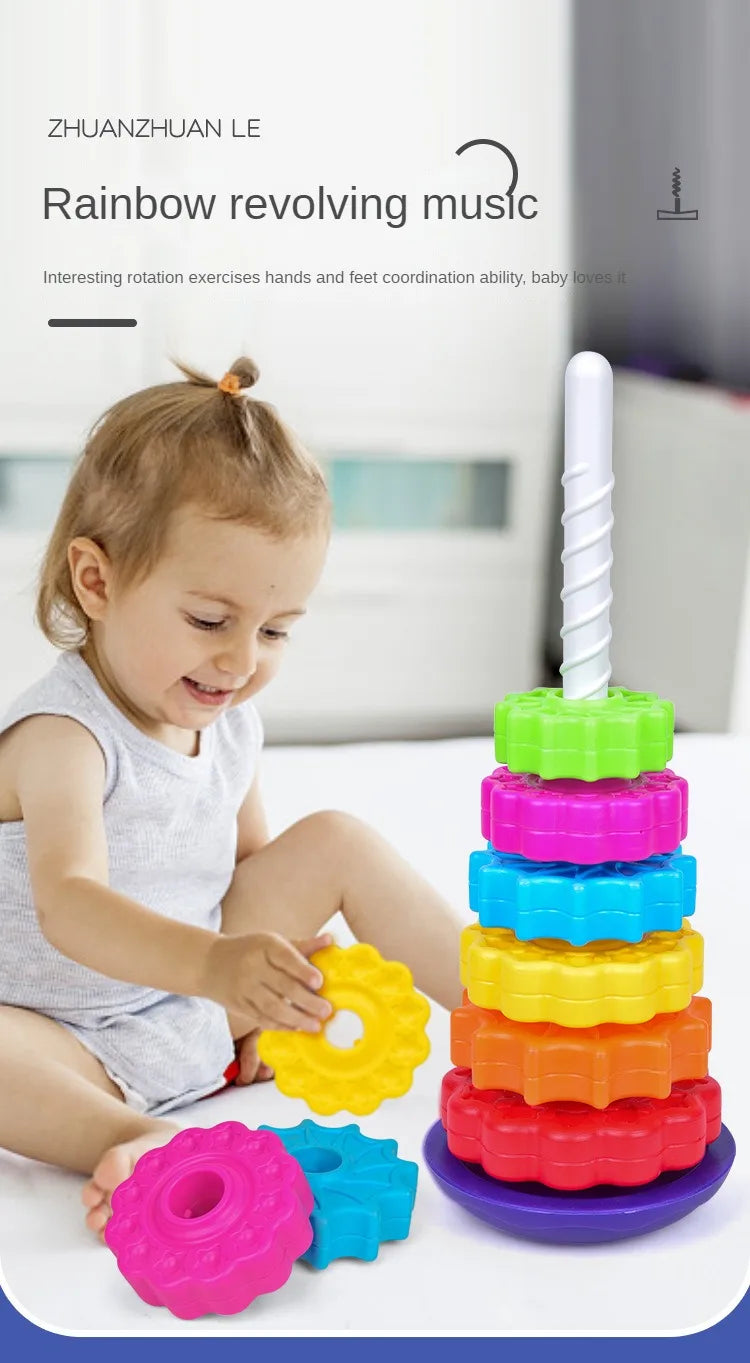 A toddler is playing with a colorful rainbow revolving music stacking toy made of plastic rings.