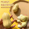 A hand holds a yellow peanut squishy stress relief toy on a beige surface.
