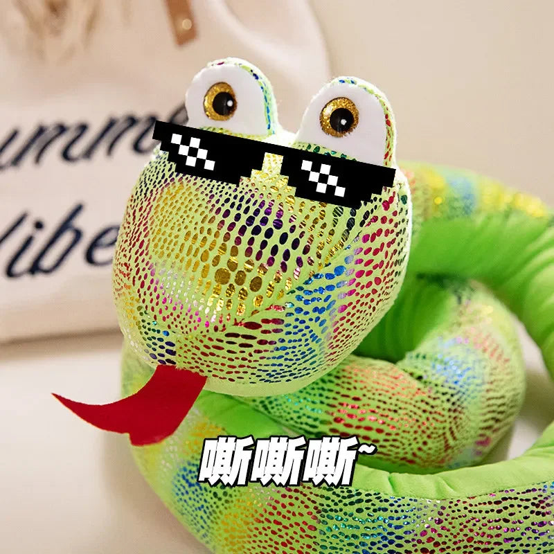 A bright green cartoon snake plush toy with large eyes wearing black sunglasses