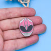 A pink and silver enamel pin featuring a dinosaur ranger battle suit and helmet design