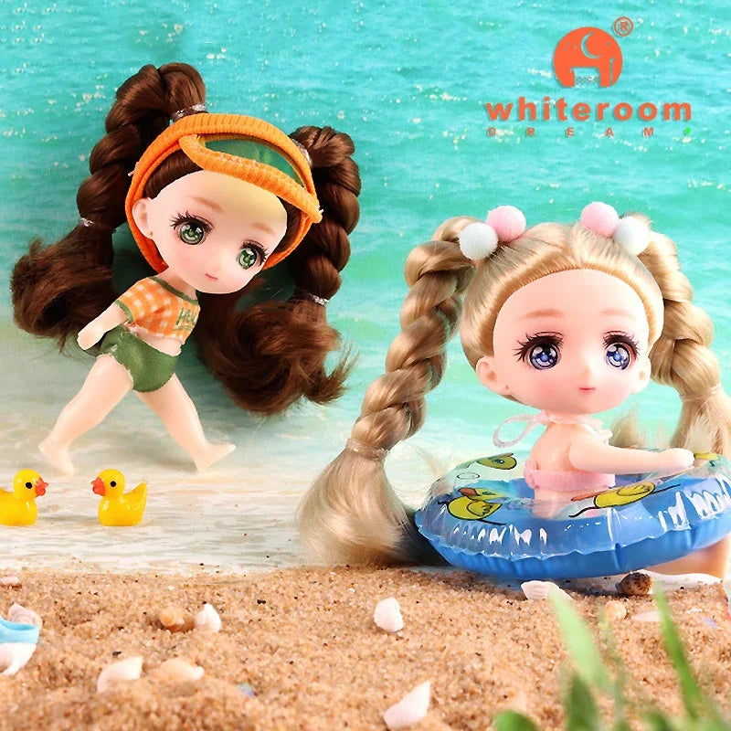 A small doll with brown hair and orange clothing is shown in a playful pose on a sandy surface.