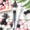 A collection of black and white silicone crafting beads arranged on a light wooden tray.