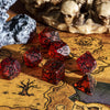 A collection of seven faceted red and black frosted resin polyhedral dice resting on aged parchment paper.