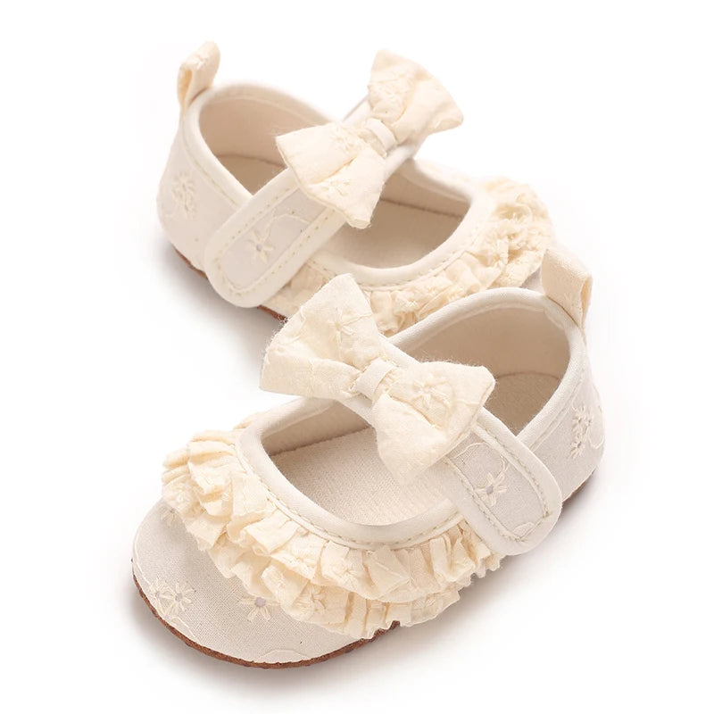 Pair of cream soft cotton baby walking shoes with bow details and anti-slip soles