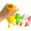 A hand is squeezing a yellow plastic duck toy with an orange beak and green accents.